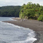 La spiaggia di sabbia nera al Danau Tolire Kecil, Pulau Ternate A black sand beach at Tolire Kecil in Pulau Ternate in the Maluku Archipelago