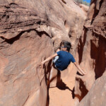 Si gioca… Kid inside Peek-A-Boo Gulch in the Dry Fork of Coyote Gulch in Grand Staircase Escalante NM in Utah USA