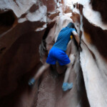 Climbing over a large Boulder in the Second Slot Section of Little Wild Horse Canyon in the San Rafael Swell Utah USA